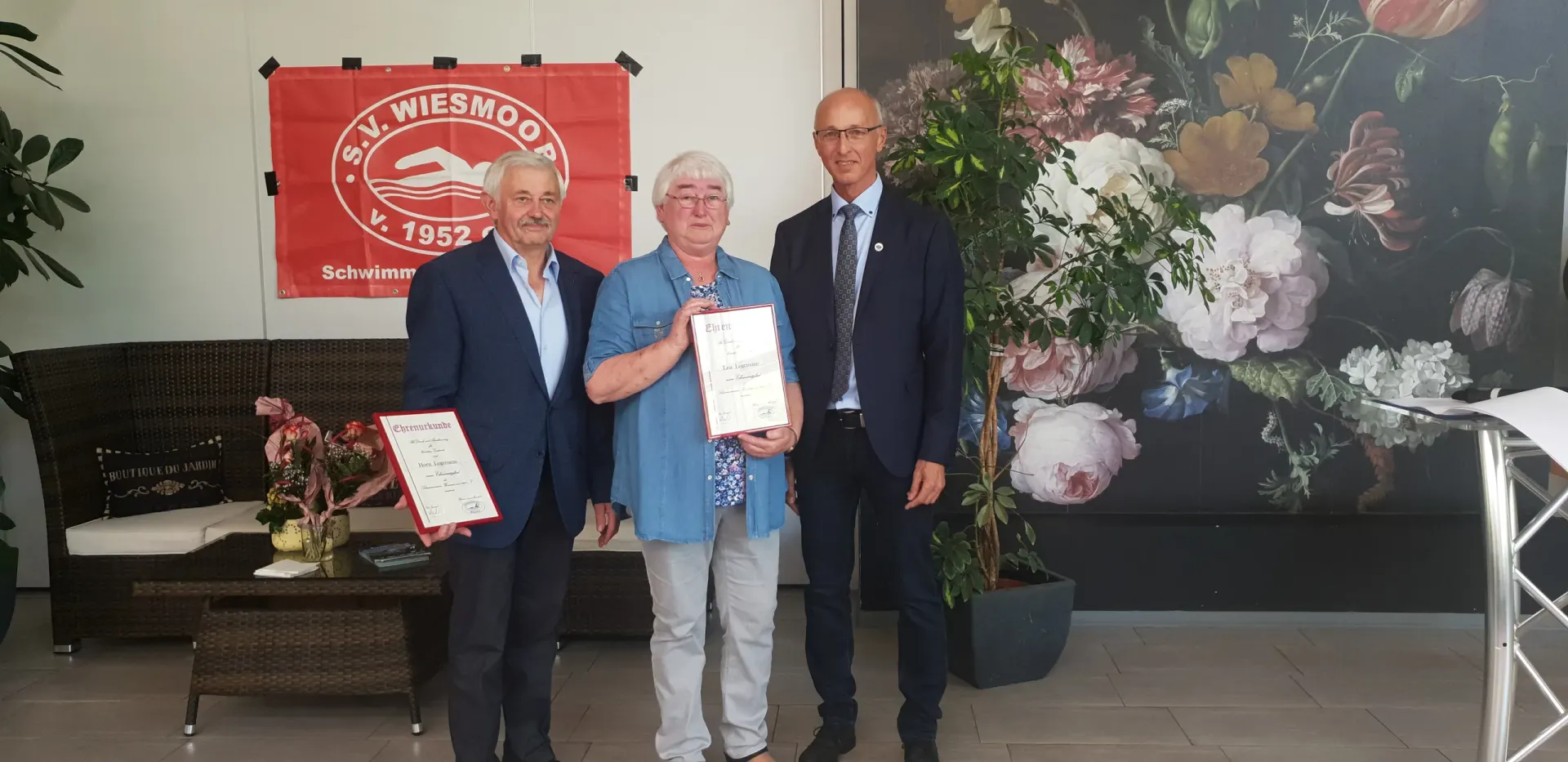 Die Ehrenmitglieder Horst und Lisa Logemann mit Urkunden vor dem roten Vereinsbanner